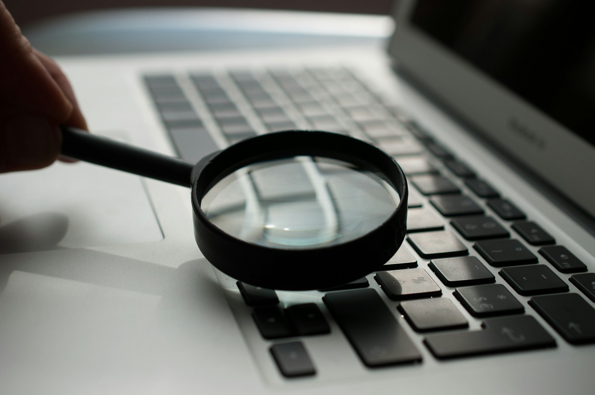Magnifying glass next to a laptop, examining a guest post listing
